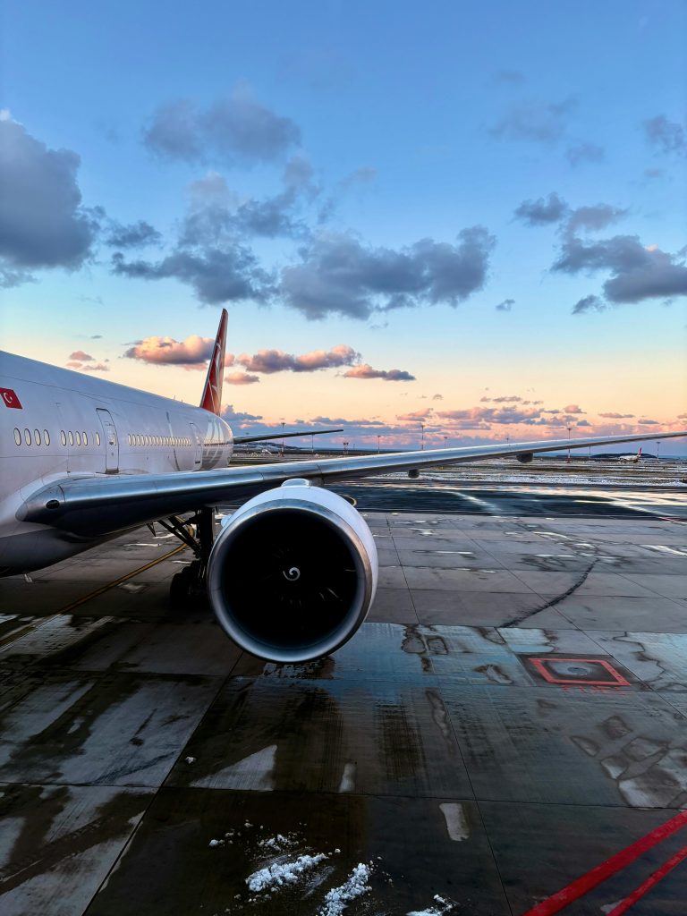 A Turkish Airlines airplane parked on the runway under a vibrant sunset sky.