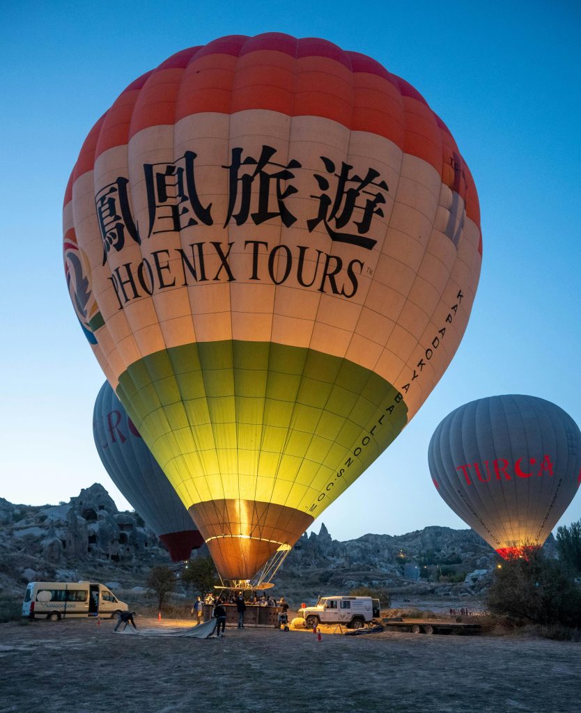 Lit hot air balloons ready for flight at dawn in Cappadocia's unique landscape.