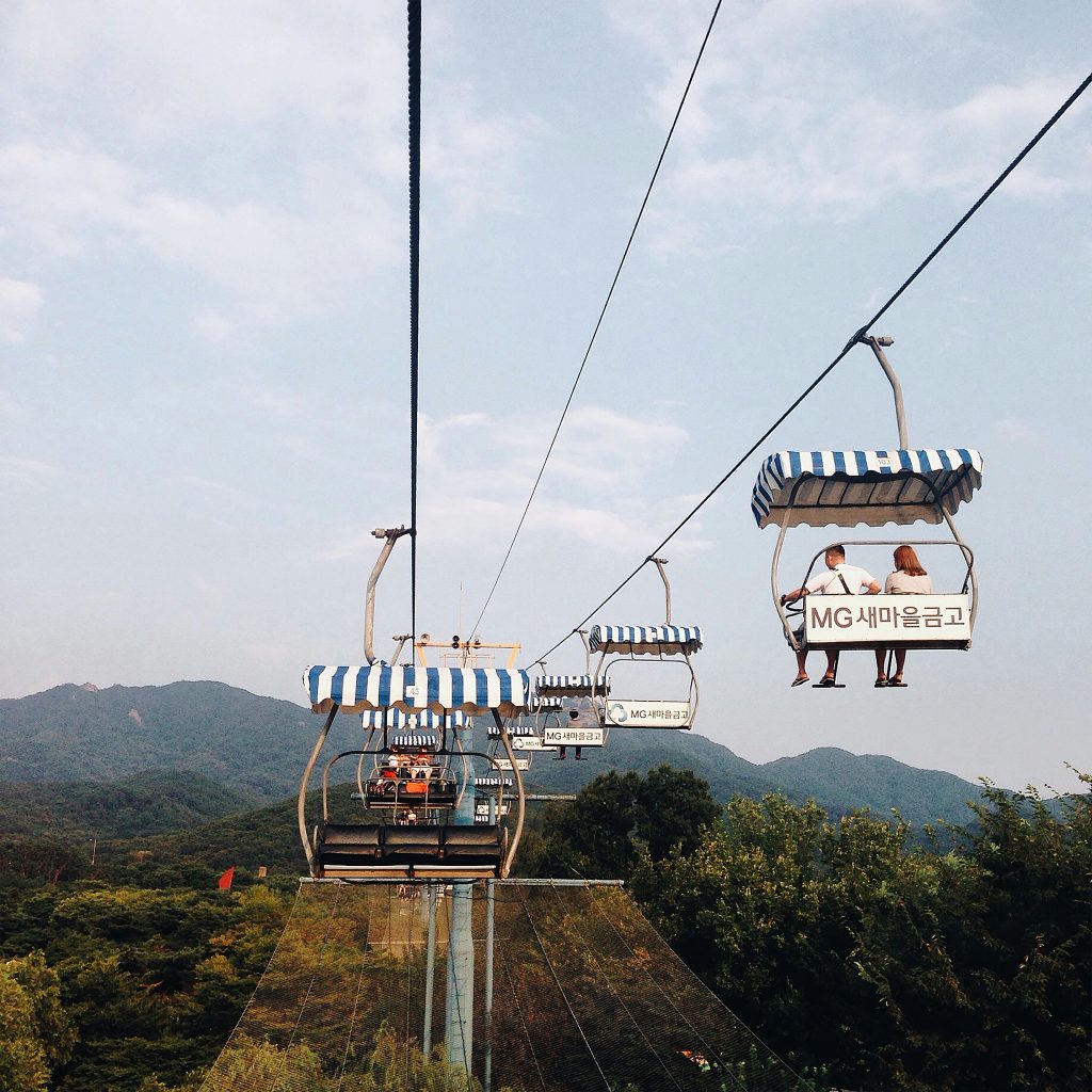 Enjoy a serene chairlift ride over lush greenery and hills in Seoul, South Korea.