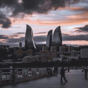 Breathtaking view of Baku's Flame Towers skyline at sunset with a vibrant pedestrian scene.